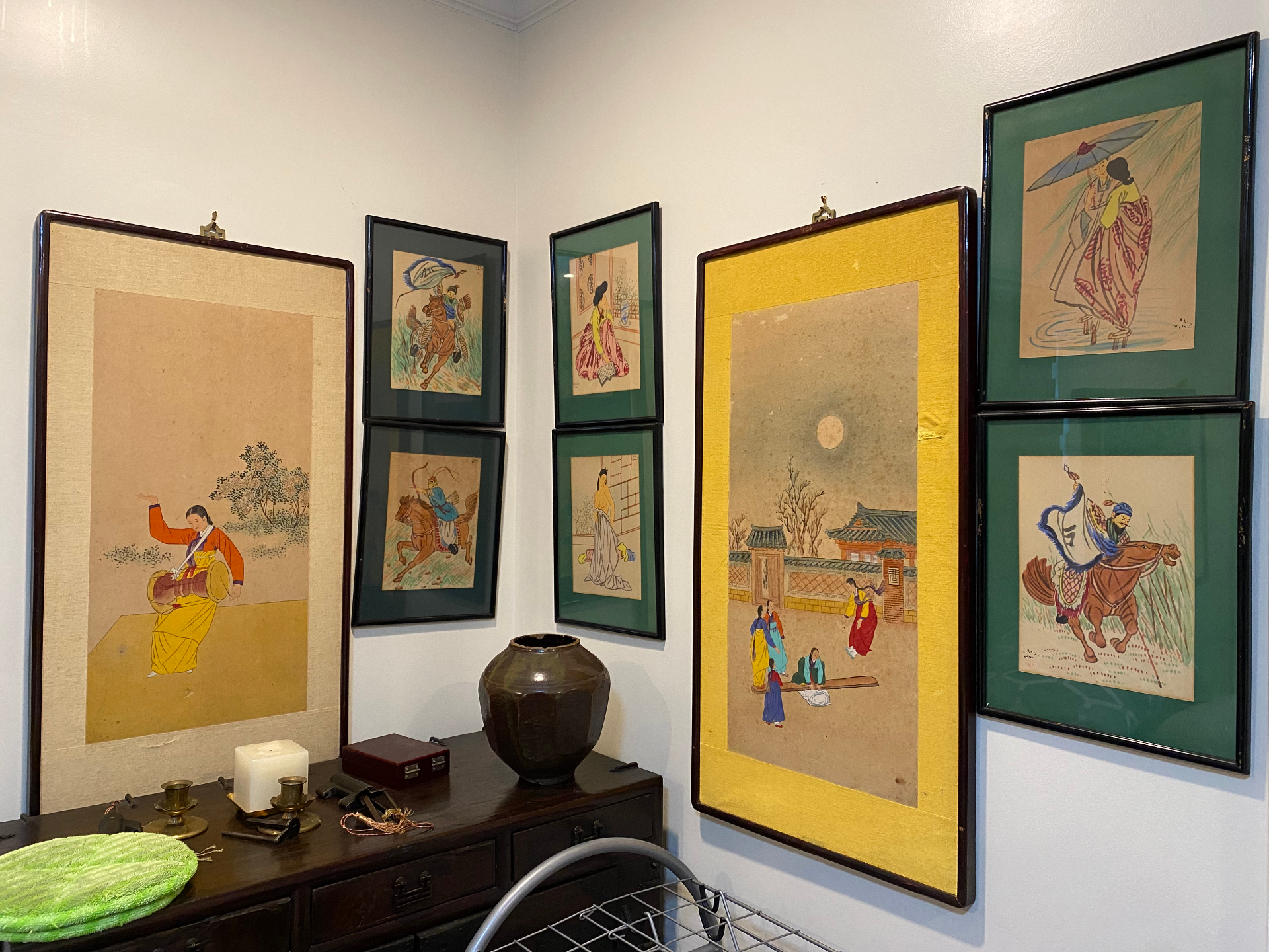 Korean folk paintings of dancers and horseback warriors framed on the wall