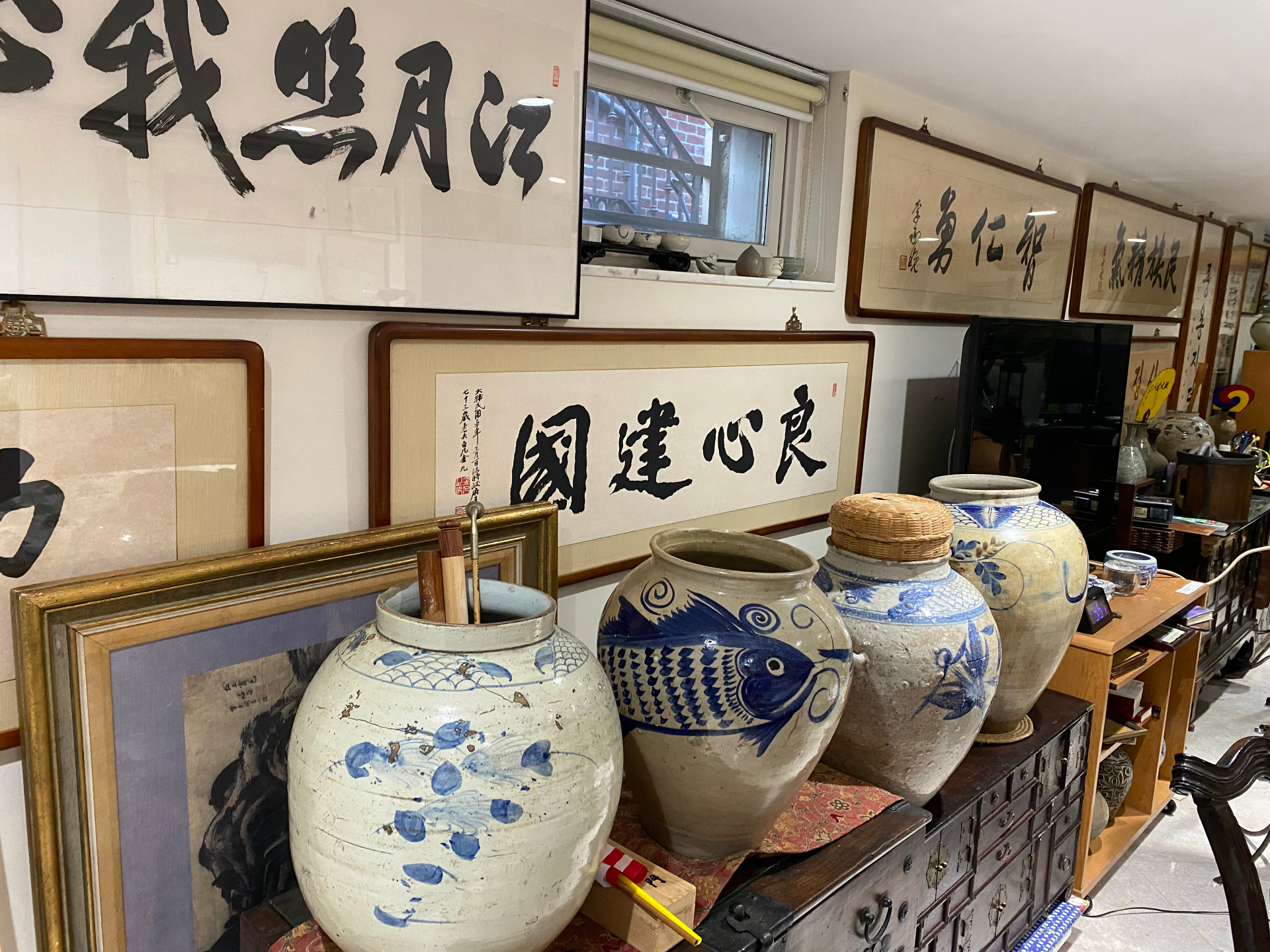 Blue and white Joseon era jars displayed beneath calligraphy panels